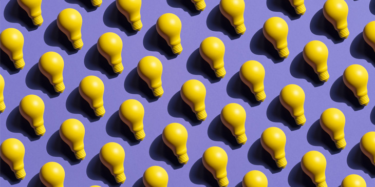 A repeated pattern of yellow lightbulbs with shadows on a purple background