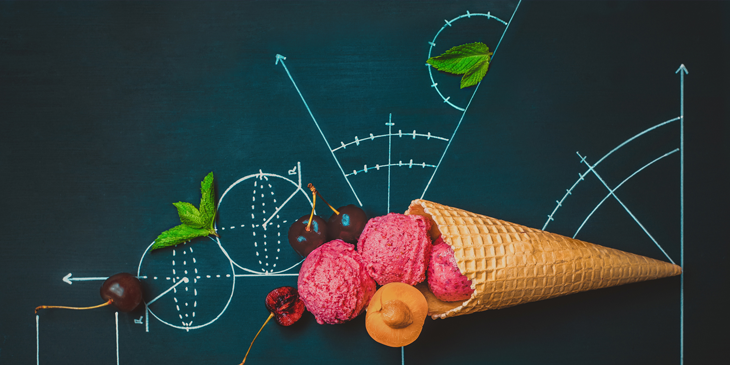 An ice cream cone with 3 scoops of ice cream, some cherries and sprigs of leaves. They are arranged on a blackboard which has a range of mathematical drawings on it