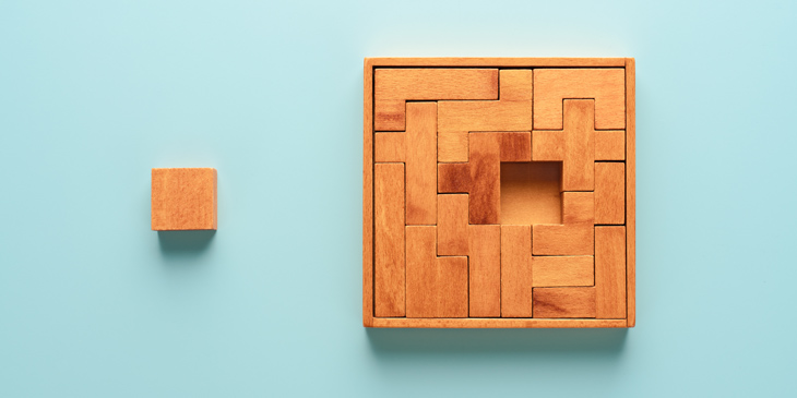 A wooden block puzzle where multiple pieces together create a square, however the middle section is removed and placed next to it