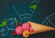 An ice cream cone with 3 scoops of ice cream, some cherries and sprigs of leaves. They are arranged on a blackboard which has a range of mathematical drawings on it