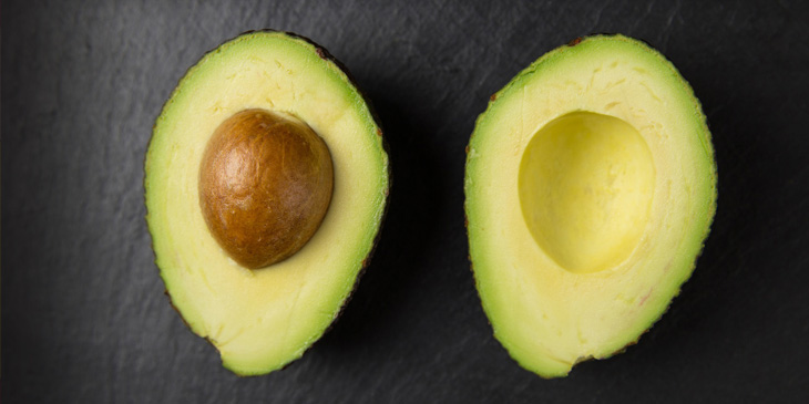 An avocado split in half to show the seed
