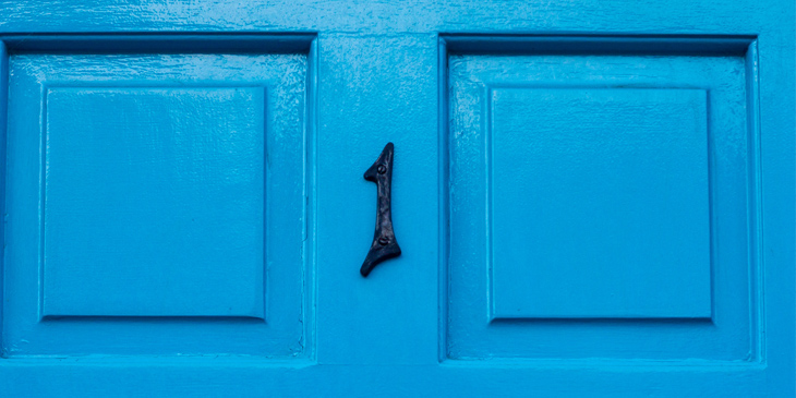 A close up of a blue front door, with the number 1 in black